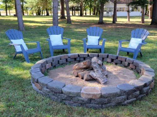 Blue Adirondack chairs around a fire pit at Whispering Pines